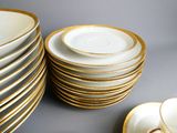 une pile d'assiettes à bord doré posée sur une table