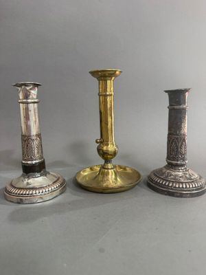 trois chandeliers en argent et en or posés les uns à côté des autres sur une table