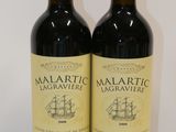 two bottles of red wine sitting next to each other on a table