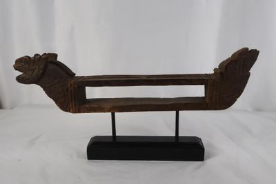 une vieille sculpture en bois représentant un oiseau, posée sur un socle noir