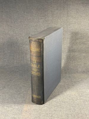 an old book sitting on top of a table next to a gray cloth