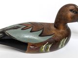 a wooden duck that is sitting on a white surface