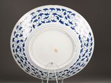 a blue and white plate on a stand on a table