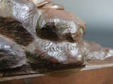 a bronze statue of a man sitting on a rock