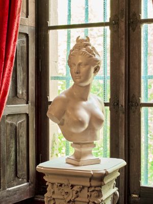 un buste de femme assise sur un socle devant une fenêtre