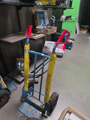 un diable bleu muni d'une poignée jaune et d'une poignée rouge