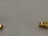 two pieces of gold chain on a white surface