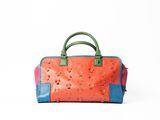 an orange and blue handbag sitting on top of a white surface