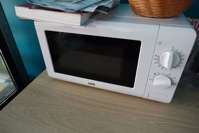 a microwave sitting on top of a table next to a basket
