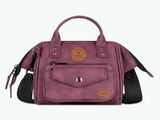 the small purple bag is on a white background and has a brown leather handle