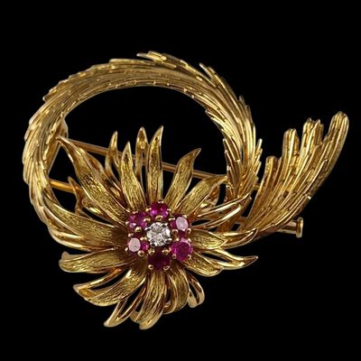 une image représentant une broche en or et rubis ornée de feuilles