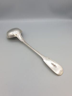 une cuillère en argent posée sur une table blanche, sur fond gris