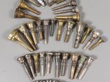 an assortment of brass and silver trumpet heads on a white surface