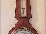 une horloge accrochée au mur, sur laquelle se trouve un baromètre
