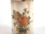 un petit vase orné de fleurs, posé sur une surface blanche