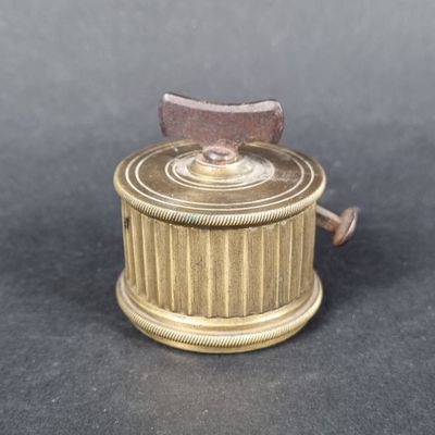 a small brass box with a wooden handle on a table