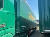 a green semi truck parked next to a green semi truck