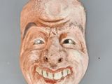 une image représentant un masque en argile représentant un homme souriant
