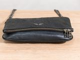 the small black purse is sitting on a wooden table