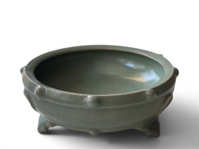 a green bowl sitting on a stand on a white surface