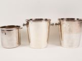 three silverplated ice buckets with handles on a white background