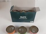 quatre boîtes de conserve dans un carton posé sur une table