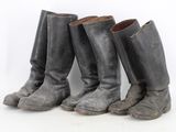 three pairs of old boots are lined up against a white background