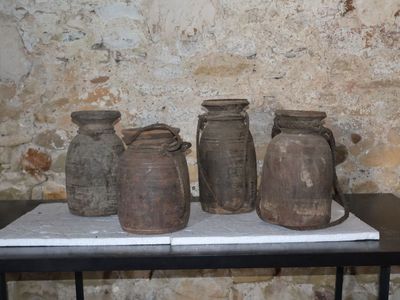 quatre vases posés sur une table devant un mur de pierre