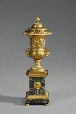 un vase doré et vert muni d'un couvercle, posé sur un socle