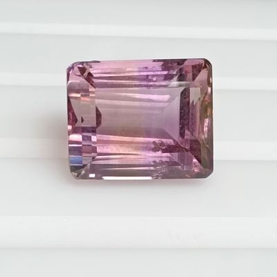 a close up of a pink tourmaline gemstone on a white surface