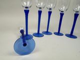 four blue wine glasses and a blue wine bottle on a white surface
