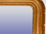 an antique gold framed mirror with a blue sky in the background
