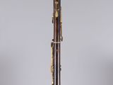 a clarinet with a wooden body and brass hardware on a clear stand