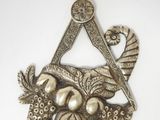 an image of a metal object with a bird and fruit on it