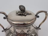 a silver tea pot with a lid on a white table