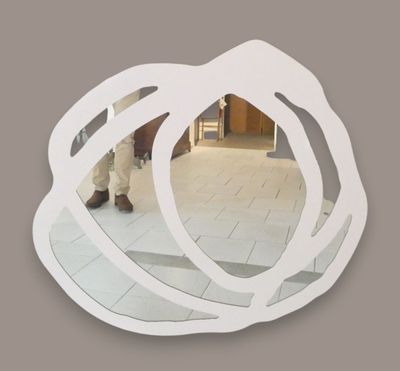 a man standing in front of a mirror that is shaped like a flower