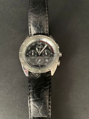 the watch is on a black leather strap on the table
