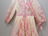 a white and pink dress hanging on a hanger on a wall