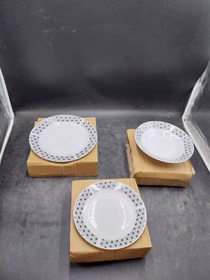 trois assiettes blanches parsemées de points noirs, posées sur une boîte