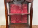 une vieille vitrine en bois surmontée d'un coussin rouge