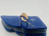 un gros plan d'une bague en or sertie d'une pierre bleue