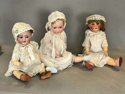 trois poupées assises ensemble sur une table