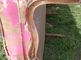 a pink couch that is sitting in the grass