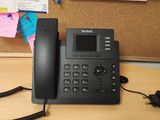 un téléphone posé sur un bureau devant un tableau d'affichage