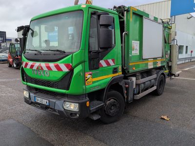 un camion-poubelle vert garé sur un parking