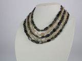 three strand necklace with black and white beads on a white mannequin