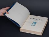 a person holding a book open on a table