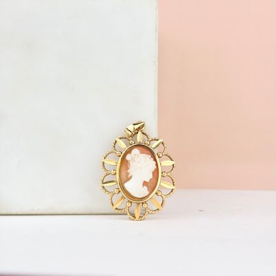 un gros plan sur une broche en or représentant le visage d'une femme