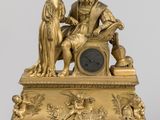 une image représentant une figurine en or d'un homme et d'une femme assis sur une horloge