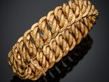 gros plan d'un bracelet en or sur une surface noire